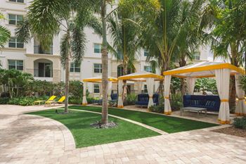 a courtyard with palm trees and yellow umbrellas in front of a building